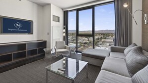 A modern living room with a sofa, armchair, and coffee table, a large window with a city view, and a mounted TV.