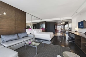 A modern hotel room with a sofa, a glass coffee table, a bed, a desk, and a TV. - Studio Mountain View | at Palms Place (Las Vegas)