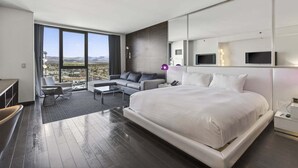 A modern hotel room with a large bed, a sofa, a desk, and a TV.