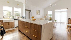 A modern kitchen with a large island, wooden cabinets, and a white countertop.