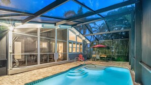A swimming pool with a glass enclosure, a patio area with outdoor furniture, and a view of palm trees. - 🌴 Palm Shade Cottage | Charming 1-Bedroom in SK, Access to Pool, Walk to Beach! (Siesta Key)