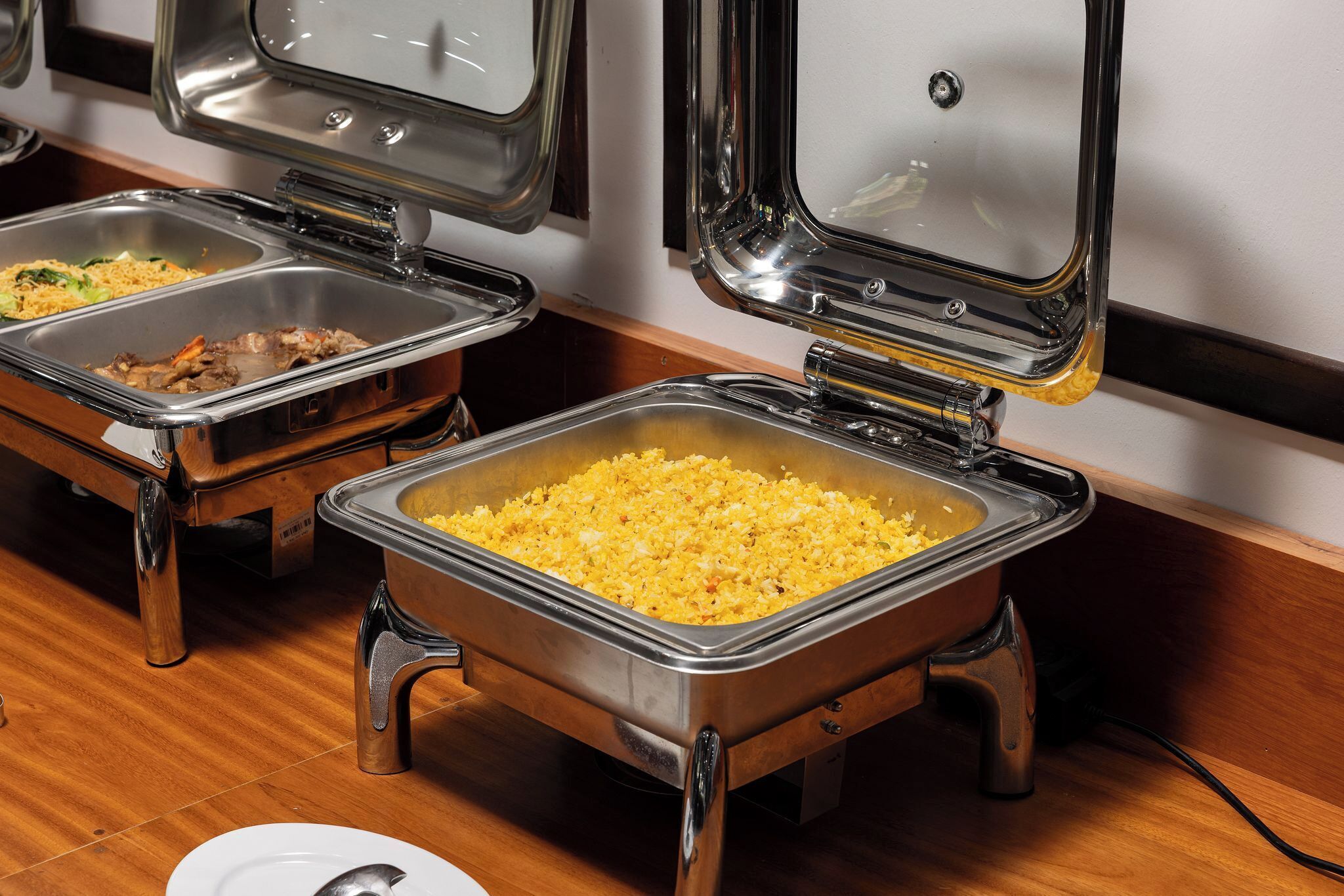 A buffet setup with multiple stainless steel chafing dishes containing various dishes.