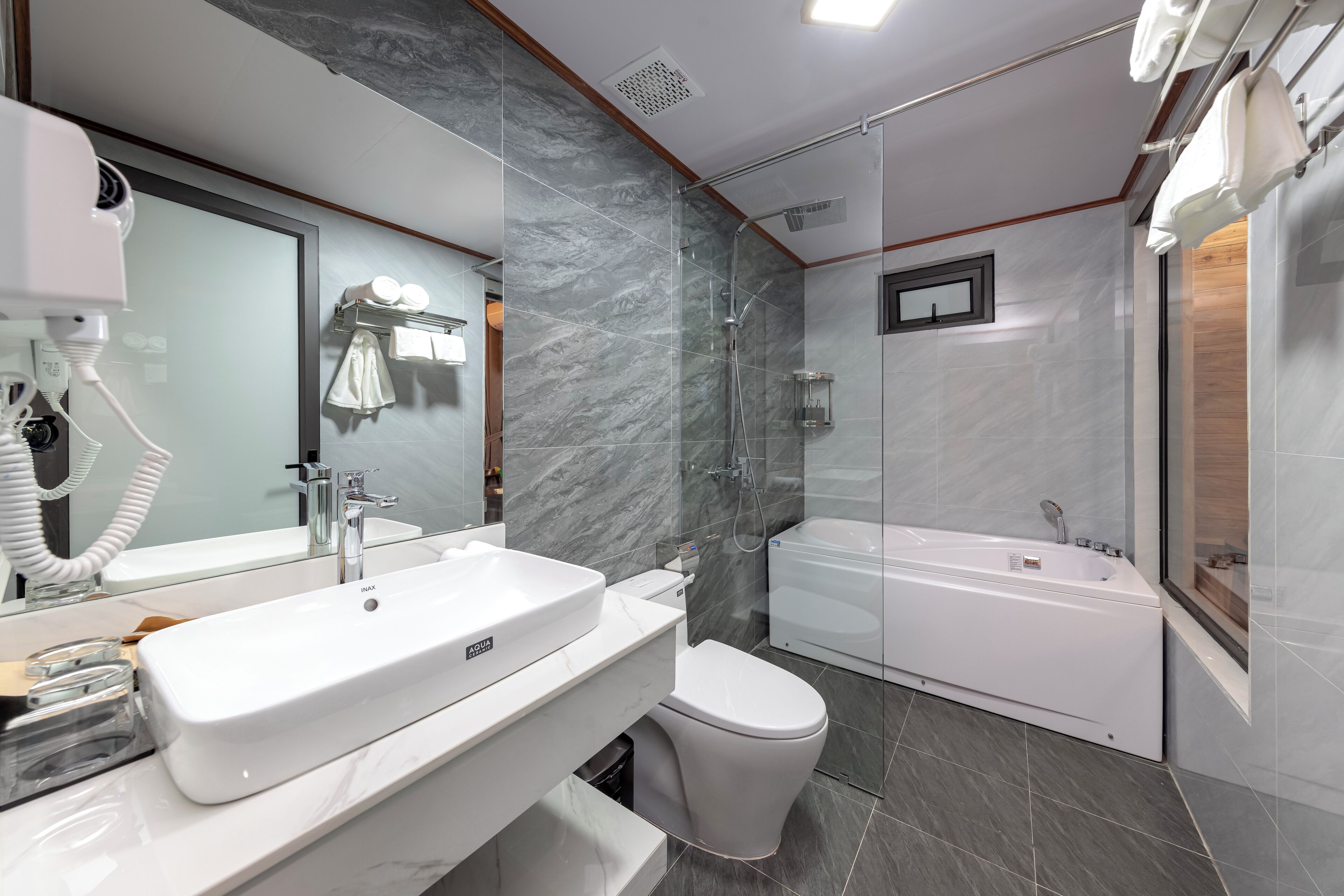 Une salle de bain moderne avec un grand miroir, un lavabo blanc, des toilettes et une baignoire.