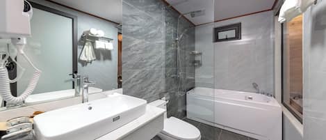 Une salle de bain moderne avec un grand miroir, un lavabo blanc, des toilettes et une baignoire.