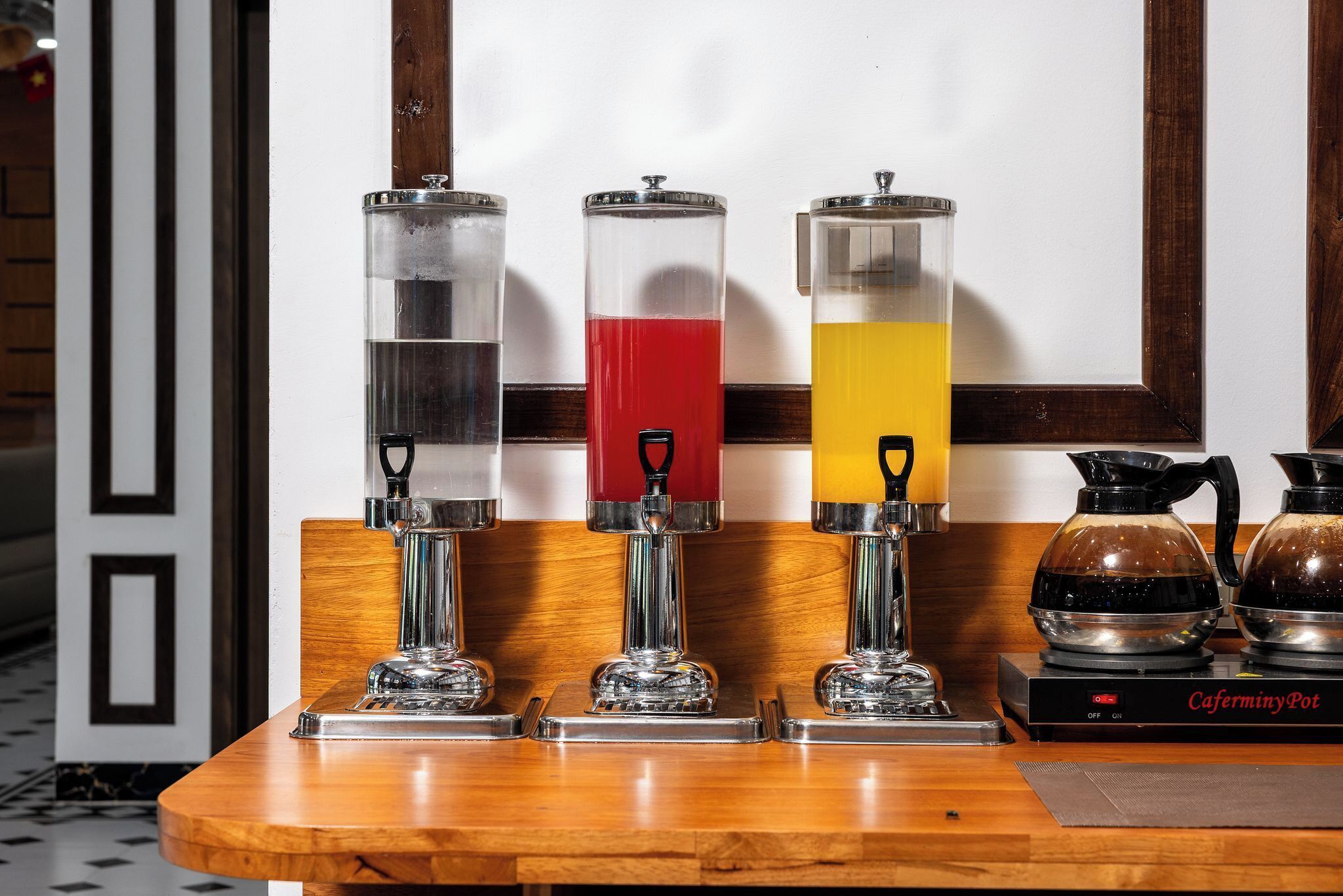 Una estación de café con tres dispensadores y una cafetera.