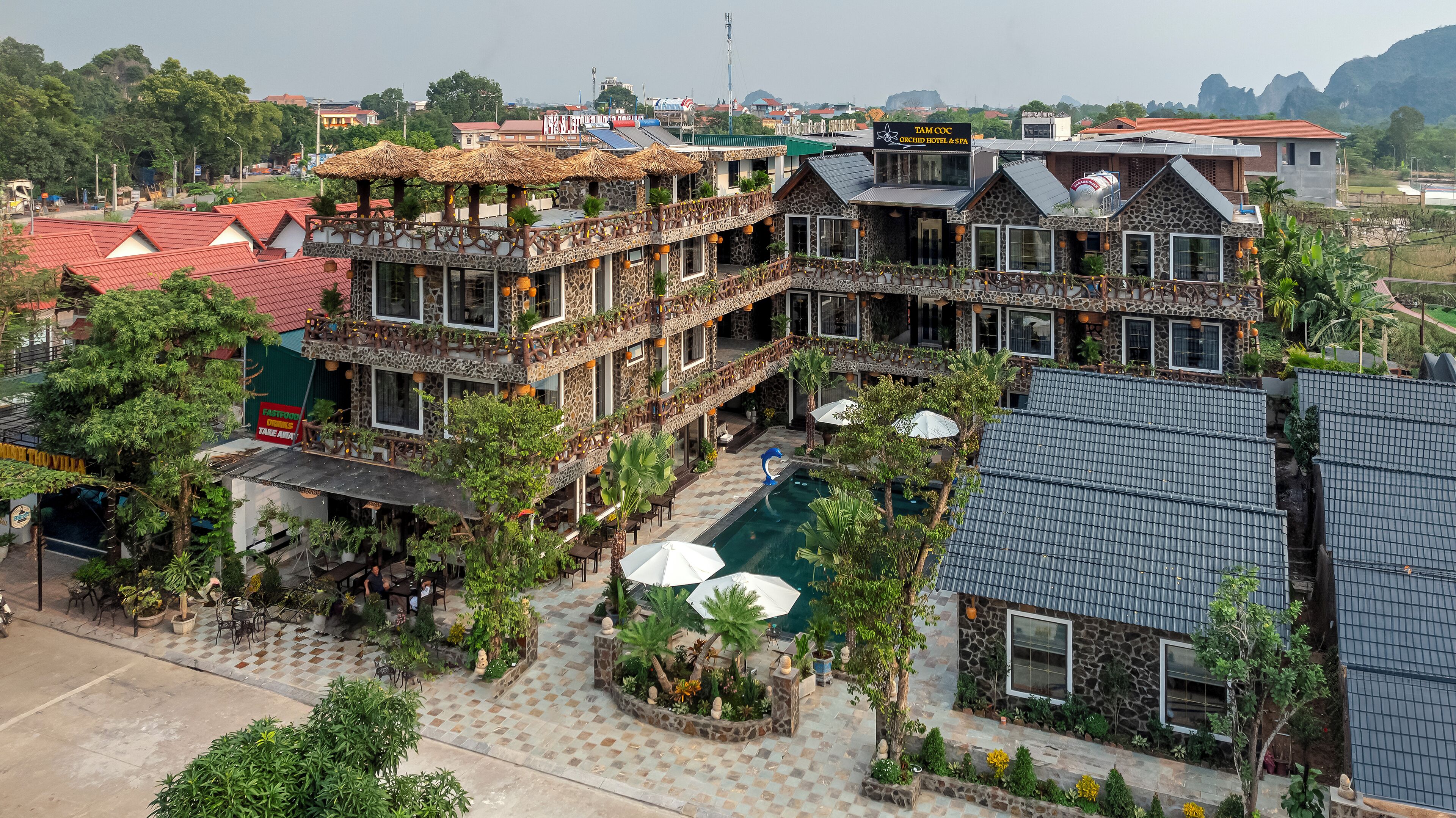 A multi-story building with a pool, outdoor seating, and a view of the surrounding area.