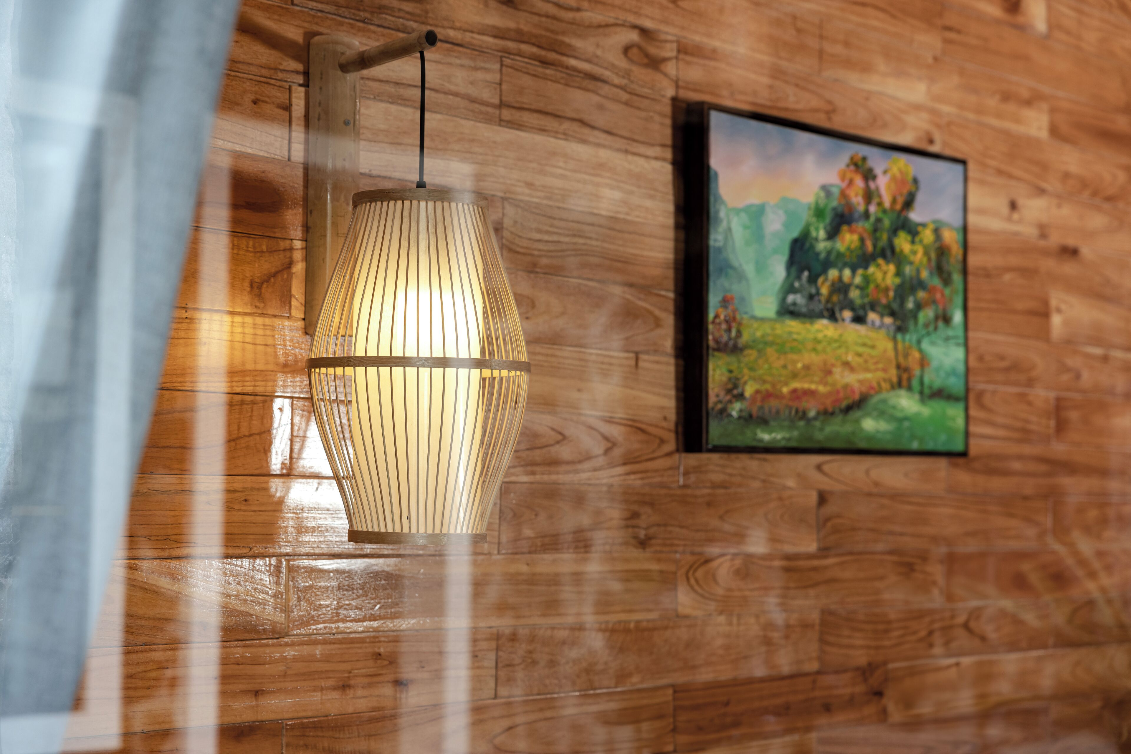 A wooden wall with a hanging light fixture and a framed painting.
