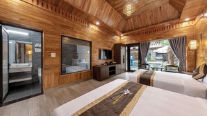A hotel room with wooden paneling, a large mirror, a TV, two beds, a desk, and a view of the outside. - Tam Coc Orchid Hotel & Spa (Nam Hoa Lu)