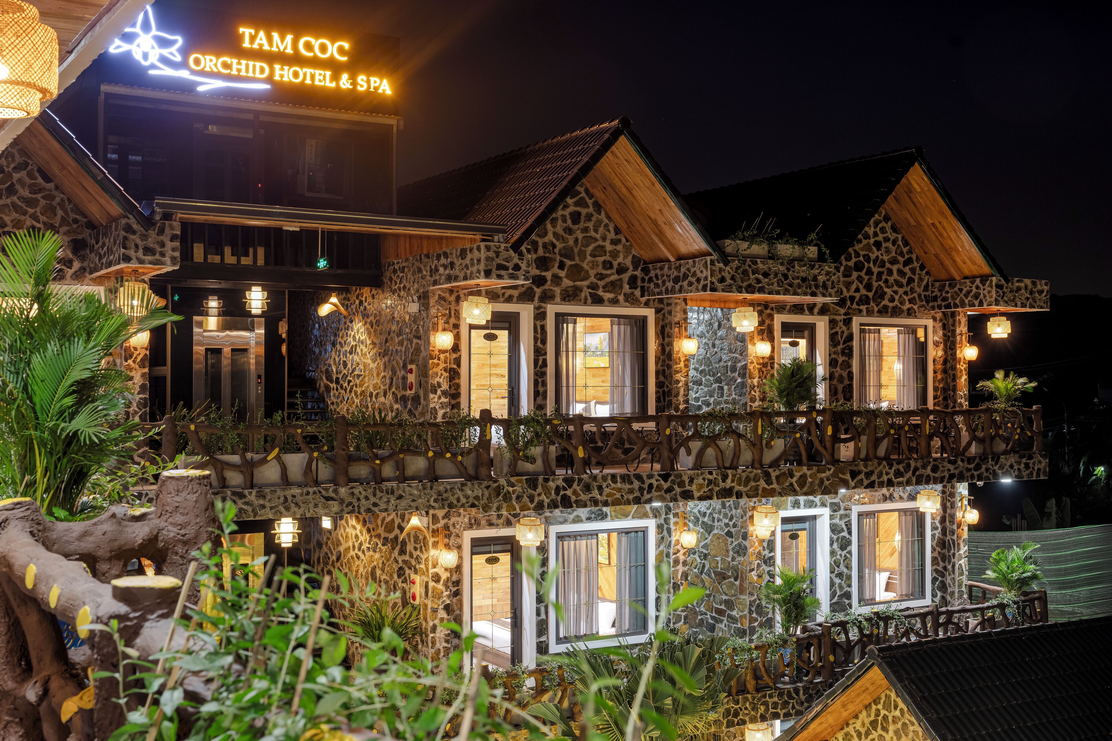 Un edificio de piedra con varios balcones y ventanas, con la leyenda "TAM COC ORCHID HOTEL & SPA".