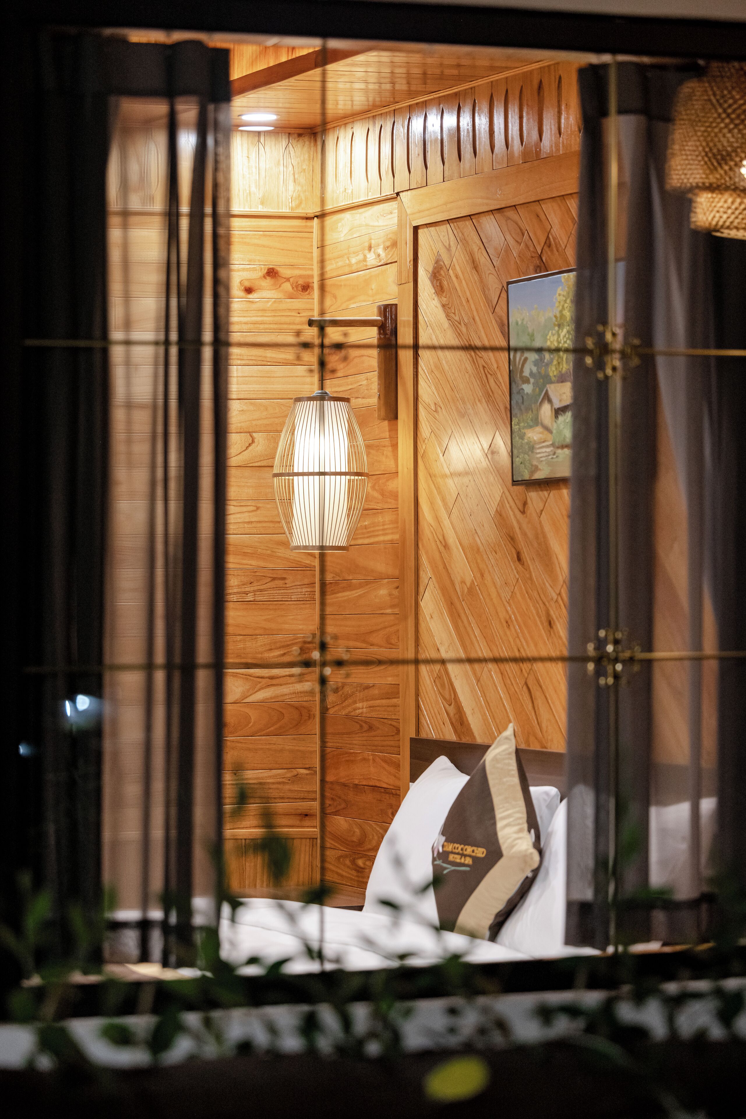 Una stanza in legno con un letto, un lampadario e un quadro appeso al muro.