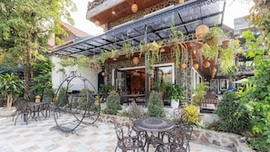 An outdoor patio with stone flooring, metal furniture, and hanging plants. - Tam Coc Orchid Hotel & Spa (Nam Hoa Lu)