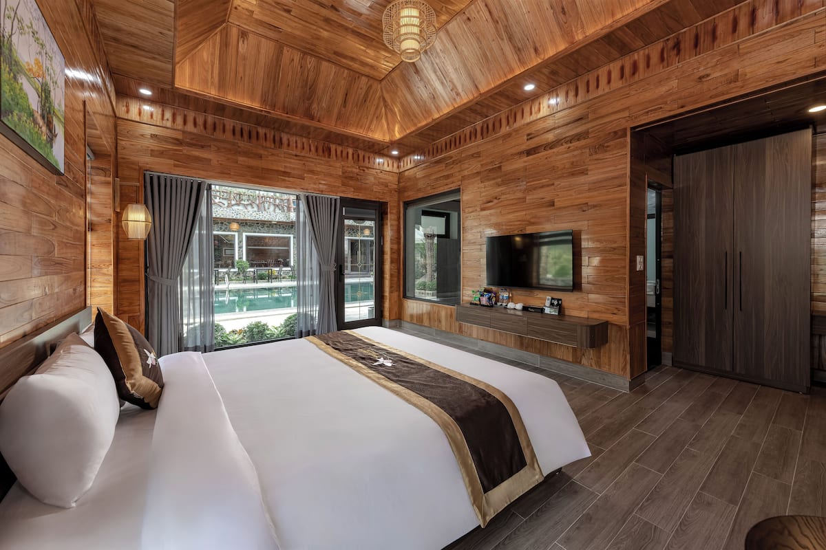 Une chambre spacieuse avec un grand lit, des murs en bois, une télévision et une armoire.
