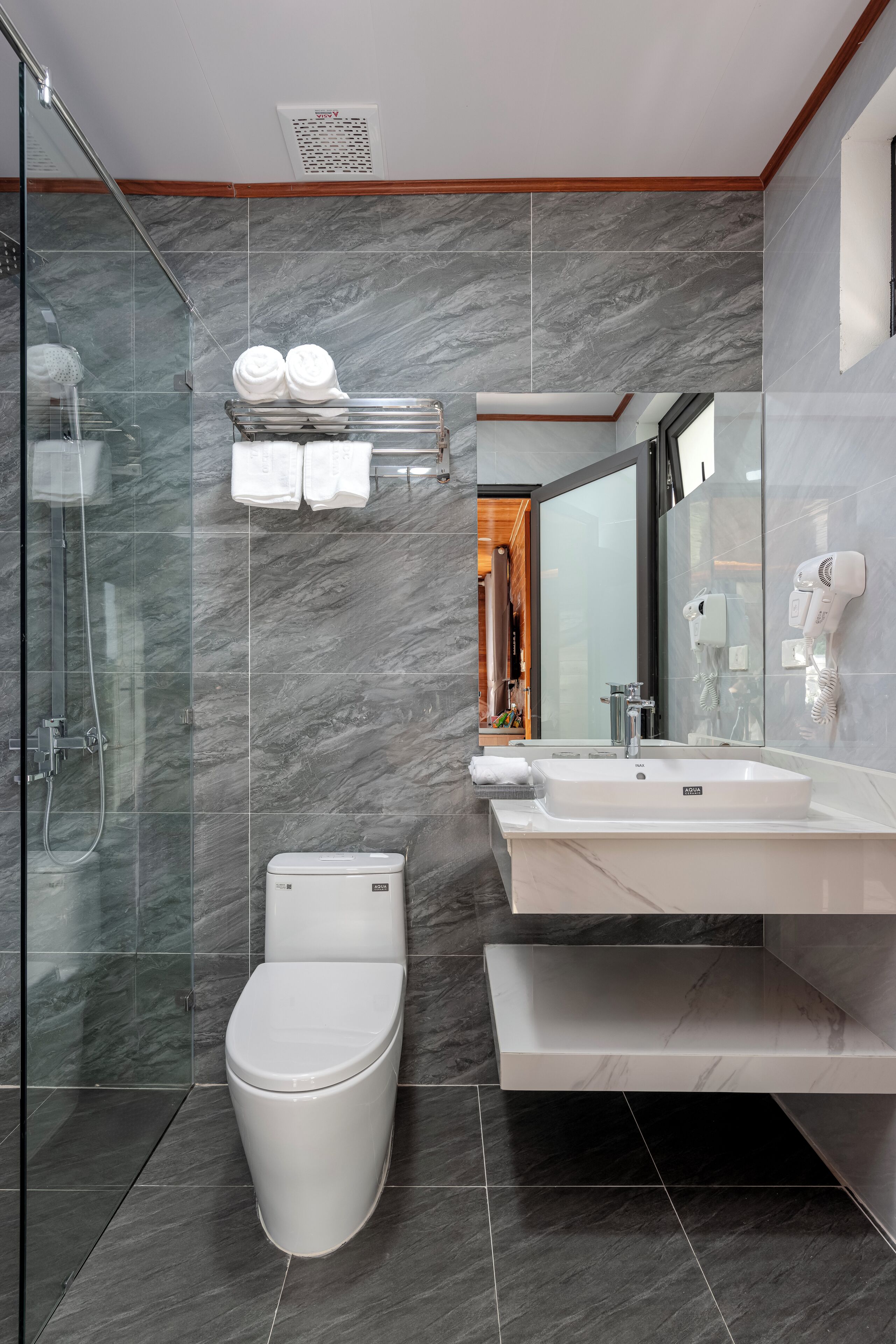 Un baño moderno con ducha envuelta en vidrio, inodoro blanco, tocador con lavabo y espejo.