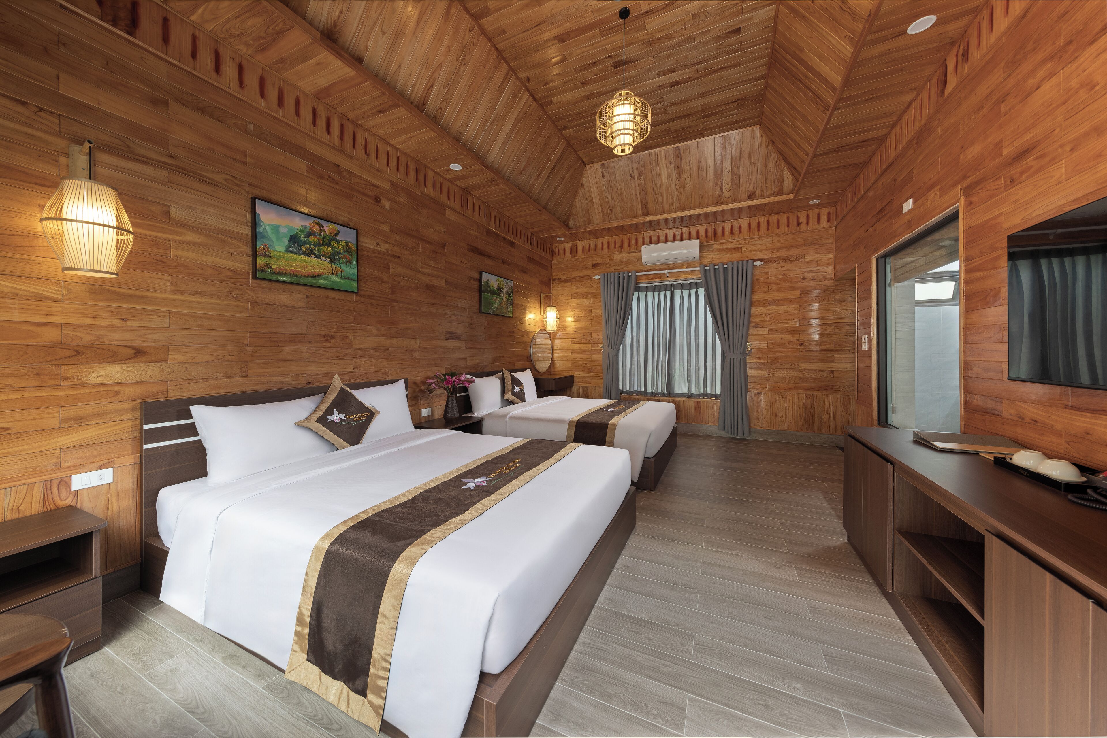 A wooden-paneled room with two beds, a desk, and a mirror.