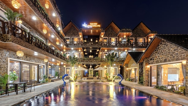 A multi-story hotel with a pool, stone facade, and outdoor seating areas. - Tam Coc Orchid Hotel & Spa (Nam Hoa Lu)