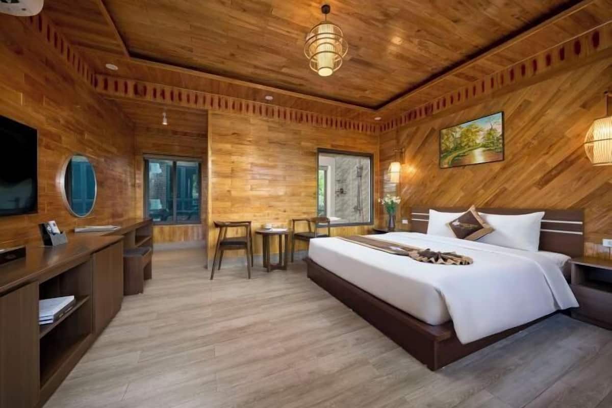 Une chambre d’hôtel à la décoration sur le thème du bois, comprenant un lit, un bureau, des chaises et un téléviseur.