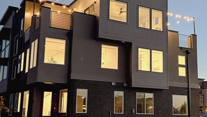 Un immeuble moderne à plusieurs étages, doté de grandes fenêtres et illuminé de guirlandes lumineuses.