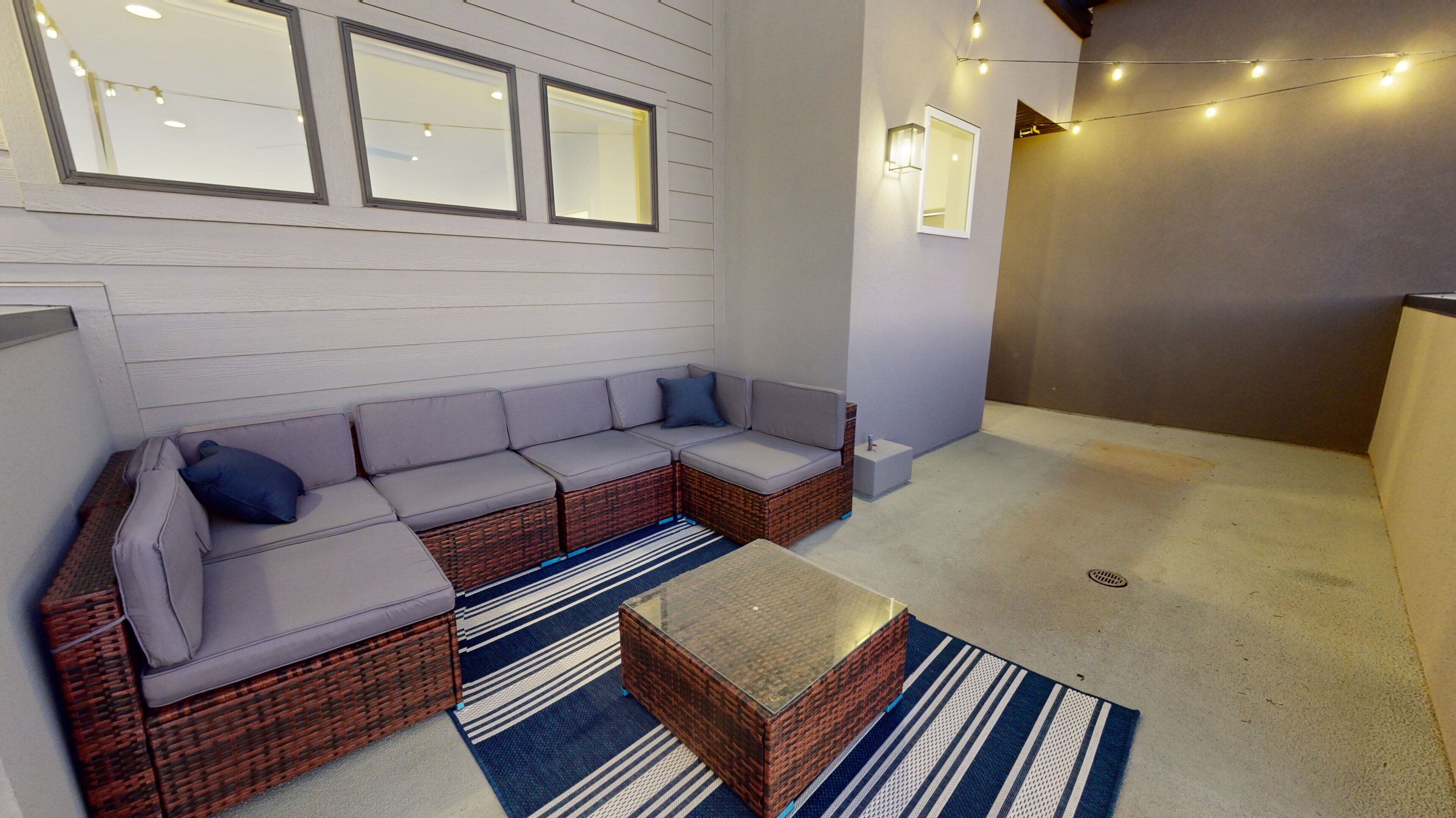A modern interior with a sectional sofa, wicker furniture, and decorative lighting.