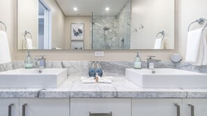 Bathroom features two sinks, a large mirror, and a marble backsplash.