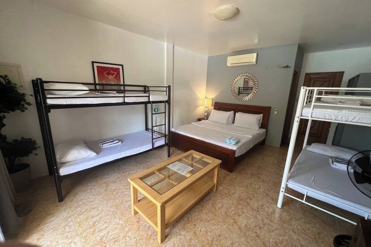 Une chambre de type dortoir, avec des lits superposés, une table basse en bois, une lampe de chevet et un élément décoratif mural.