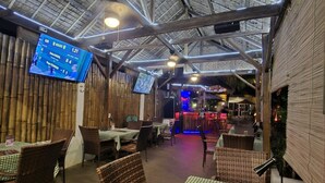 Un restaurant intérieur avec de hauts plafonds, des murs en bambou et des nappes à carreaux.