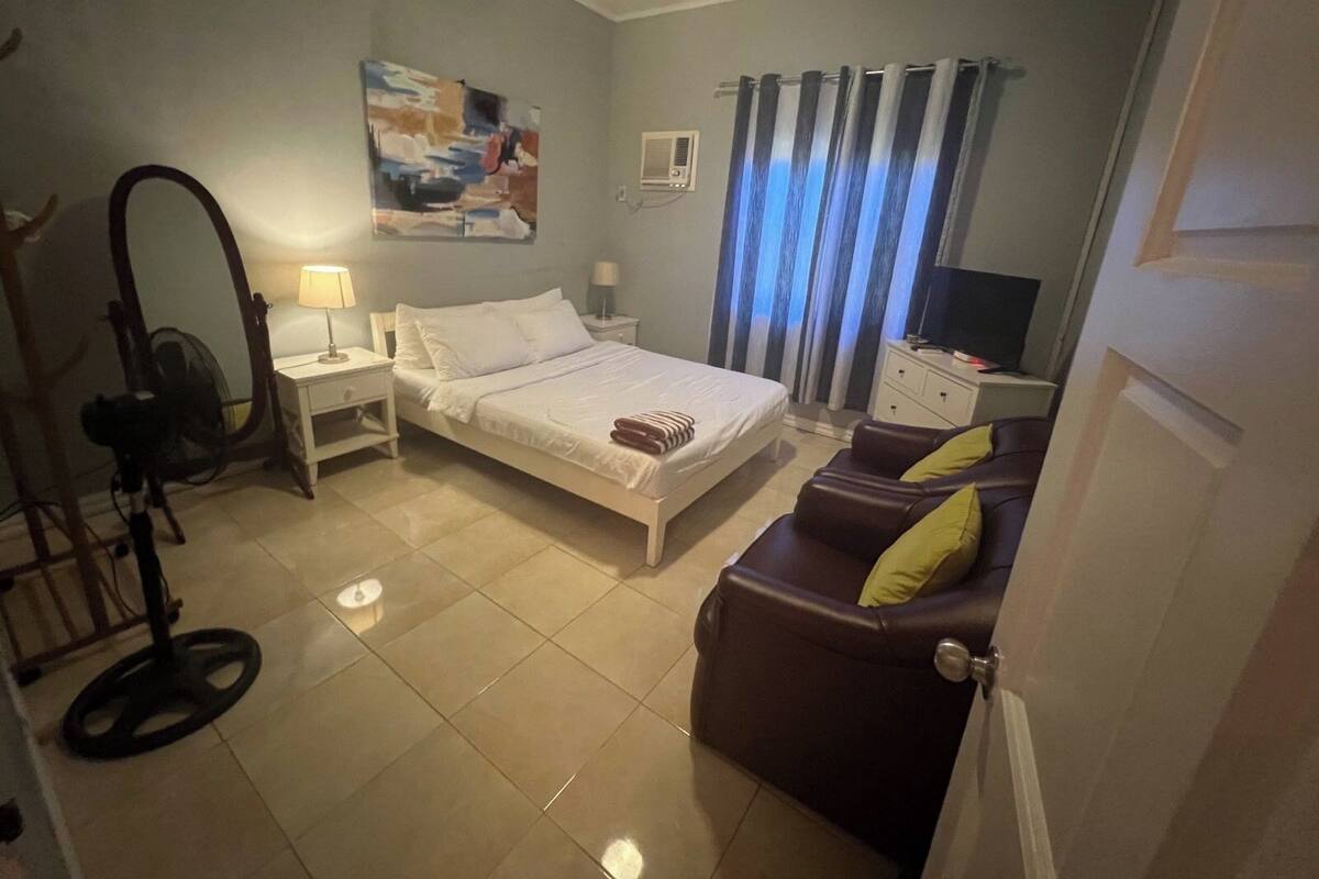Une chambre à coucher avec un lit, un bureau, une chaise, un téléviseur et un tableau accroché au mur.