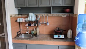 Una cocina con gabinetes grises, un fregadero, una estufa y un hervidor.