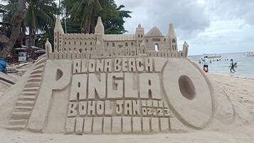 Un castello di sabbia con la scritta 'ALONA BEACH PANGLA' e 'BOHOL GEN 02-23' incisa.