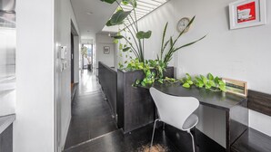 A modern kitchen with a black countertop, white chair, and large green plants. - TOWNHOUSE ASAHIKAWA  (Asahikawa)