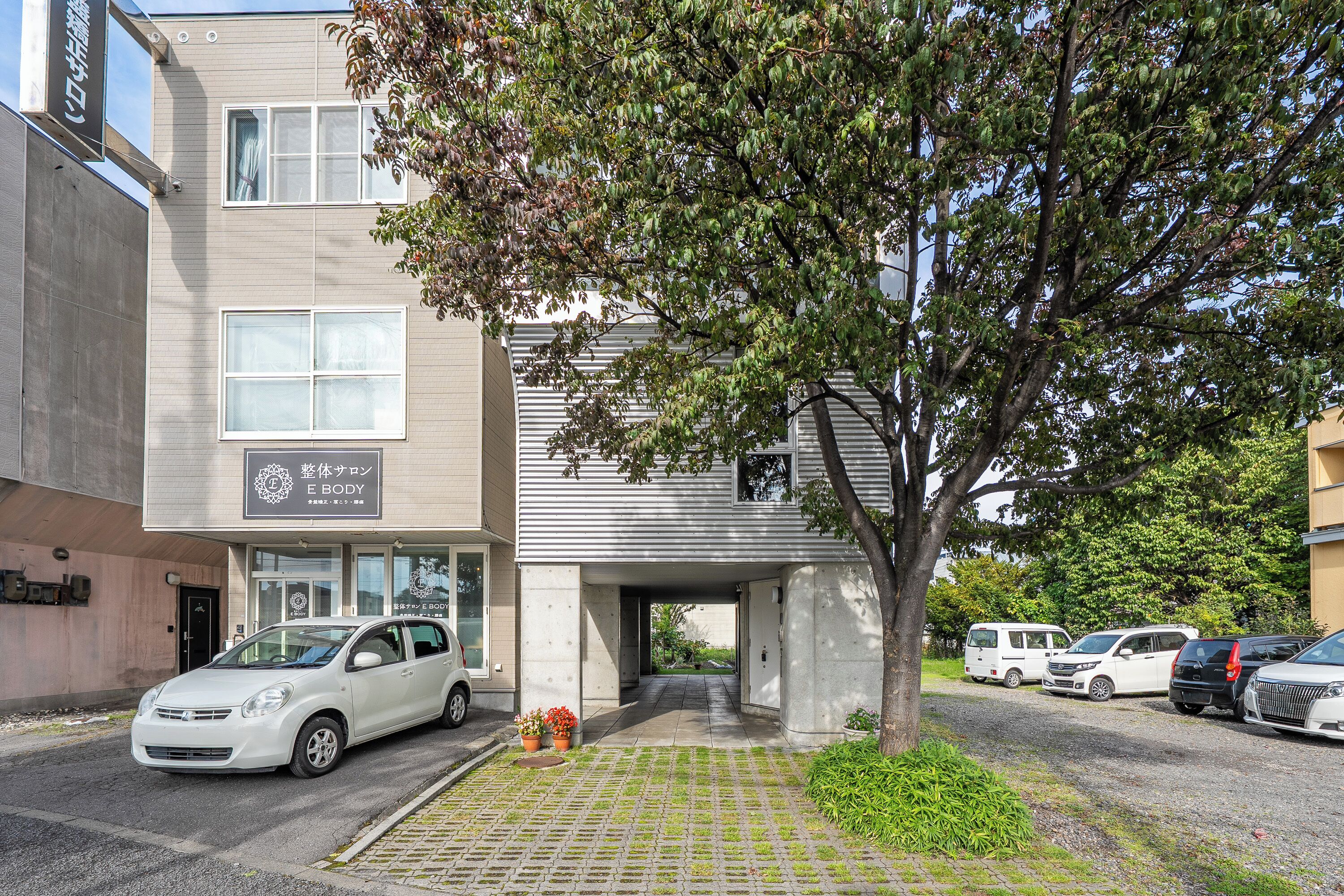 A building with a sign for 'E BODY' and a parking area with cars.