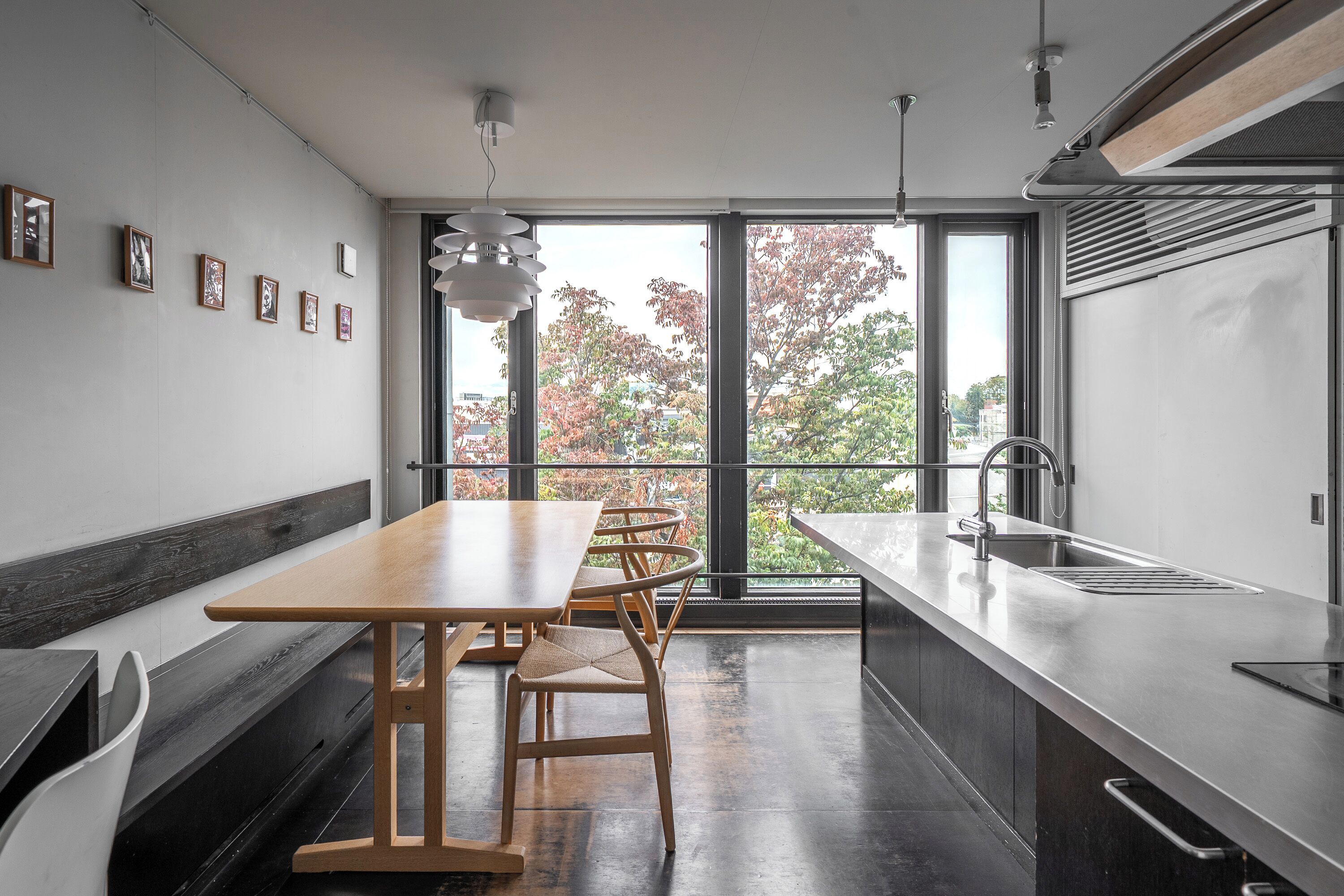 A modern kitchen with a long counter, a sink, and a dining area with a bench and chairs.