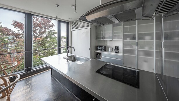 A modern kitchen with a large island, stainless steel appliances, and a view through large windows. - TOWNHOUSE ASAHIKAWA  (Asahikawa)