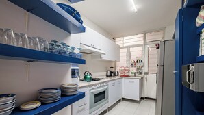 A kitchen with white cabinets, blue shelves, and a stainless steel refrigerator.