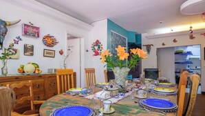 A dining area with a round table set for four, surrounded by wooden chairs.