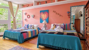 A bedroom with two beds, a large window, and a ceiling fan.