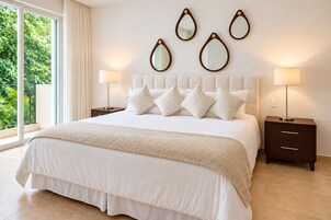Habitación de hotel con una cama grande, dos mesitas de noche y vistas a zonas verdes por la ventana.