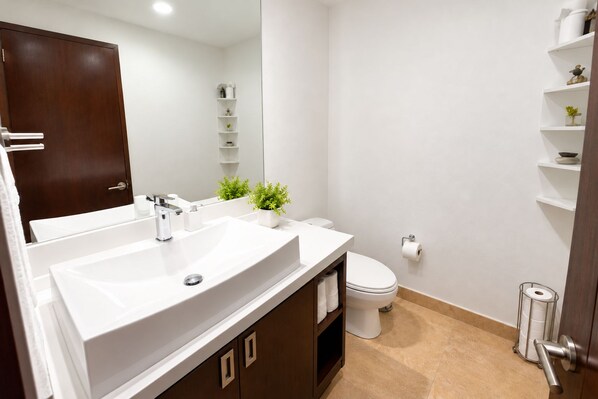 A modern bathroom with a double sink, toilet, and a mirror.