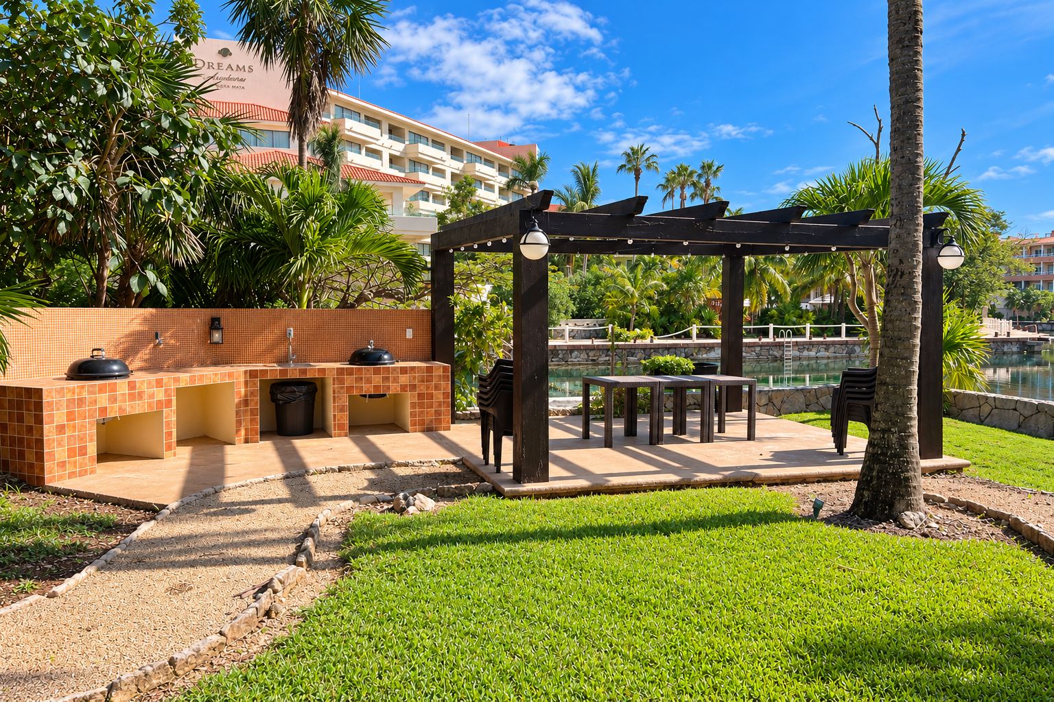 An outdoor patio area with a barbecue station, seating, and a view of a body of water.