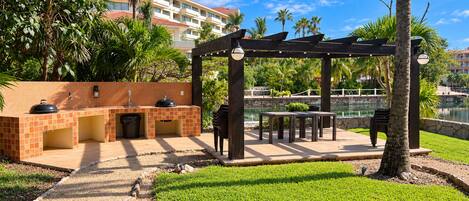 An outdoor patio area with a barbecue station, seating, and a view of a body of water.