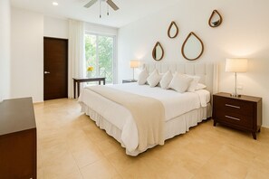A bedroom with a large bed, bedside tables, a desk, and a window with curtains. - High-End Waterfront Condo Secrets Waters (Puerto Aventuras)
