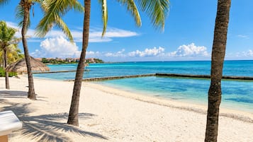 Ein Strand mit klarem türkisfarbenem Wasser, Palmen und einem Sandstrand.