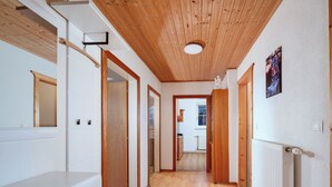 A hallway with wooden floors, white walls, and a wooden ceiling. There are doors leading to other rooms, and a radiator on the right wall. - Ferienwohnung Grimmingblick by Interhome (Öblarn)
