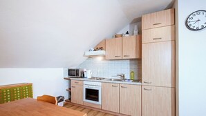 A compact kitchen with wooden cabinets, a microwave, a kettle, and a sink. - Ferienwohnung Grimmingblick by Interhome (Öblarn)