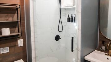 A modern bathroom with a glass-enclosed shower, a white toilet, and a vanity with a mirror.