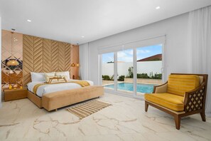 A bedroom with a large bed, a view of a swimming pool, and a chair.