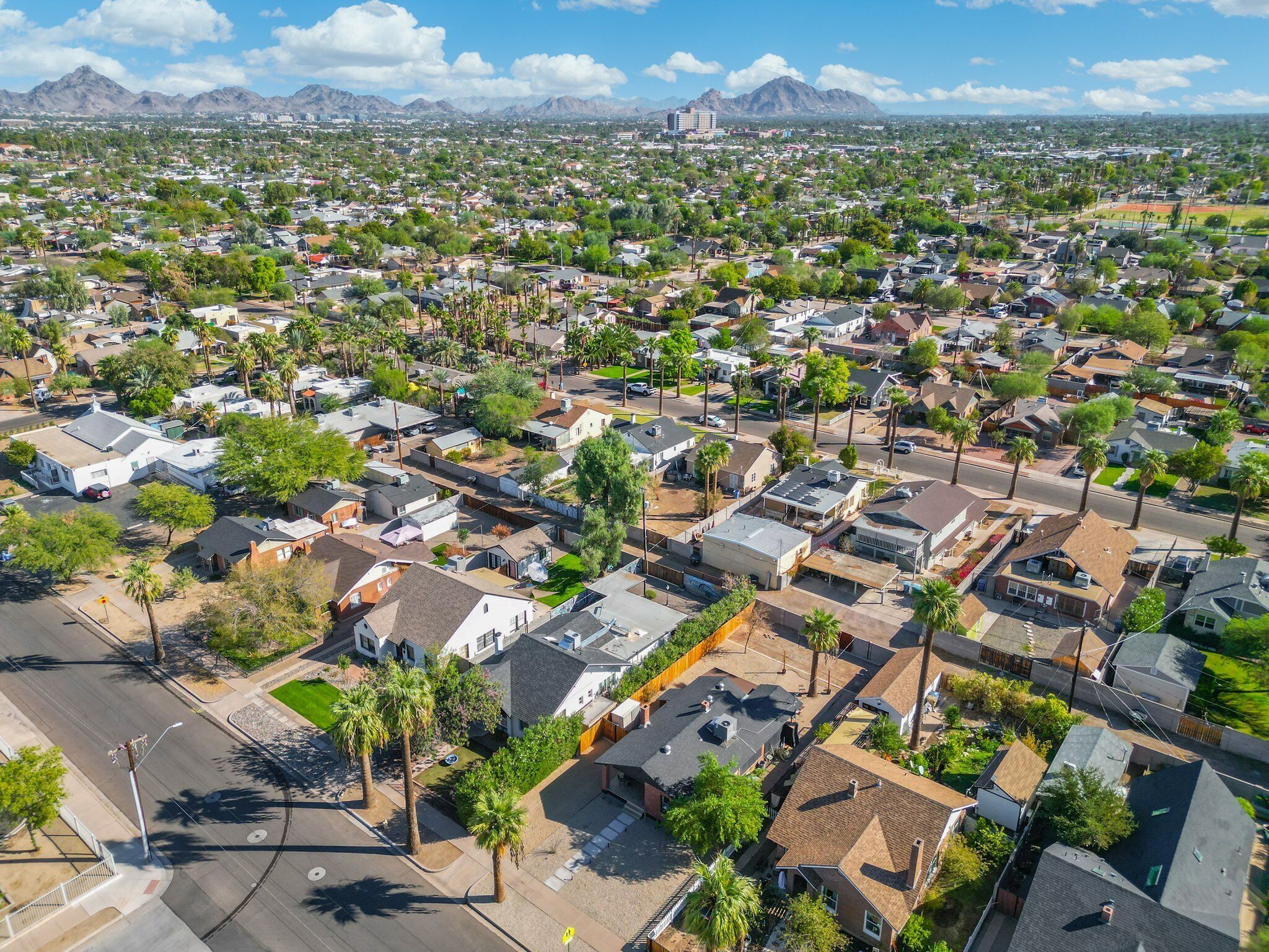 An aerial view of a residential area with houses, streets, and palm trees.