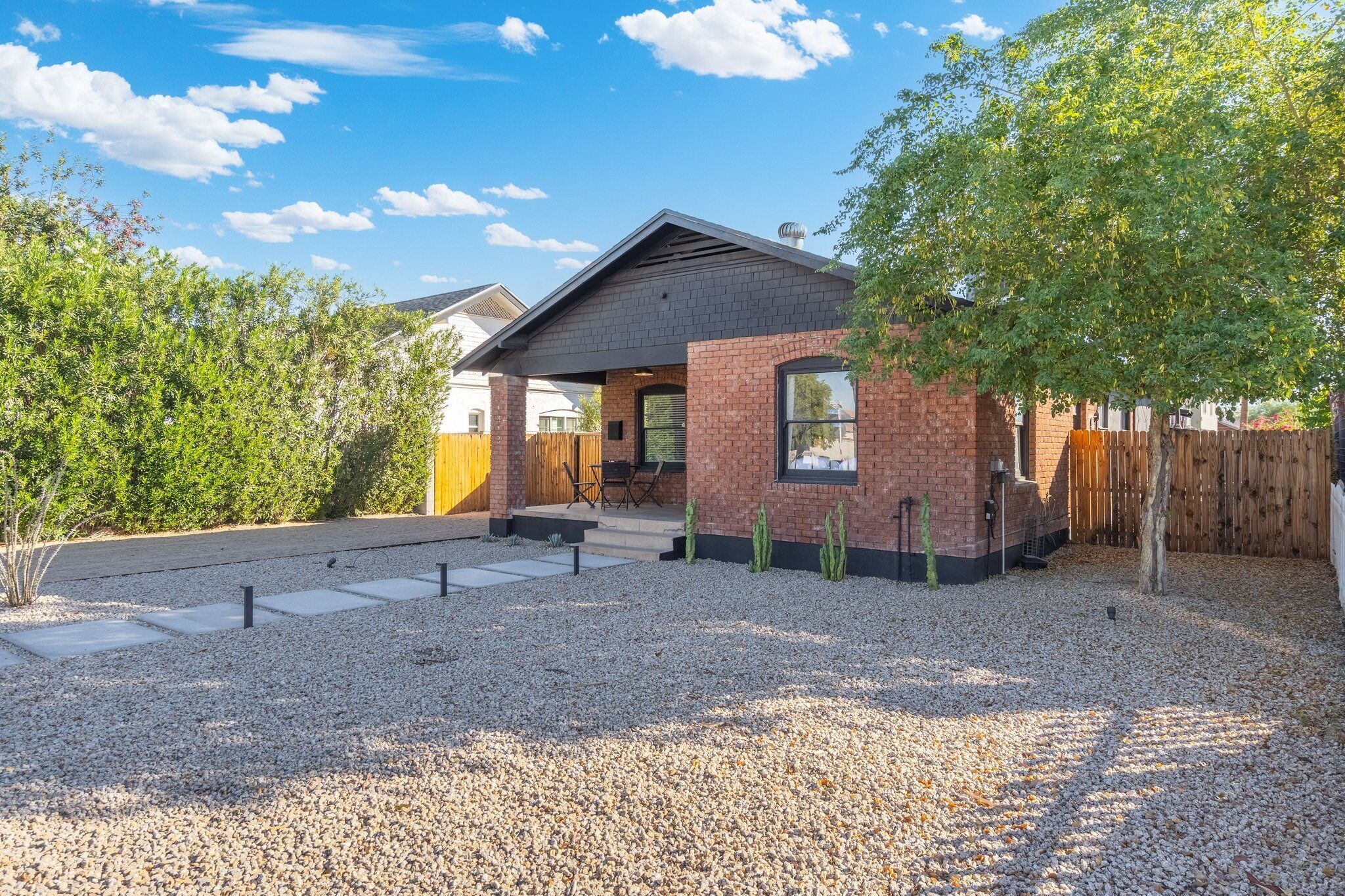 A modern house with a brick exterior, a wooden deck, and a gravel driveway.