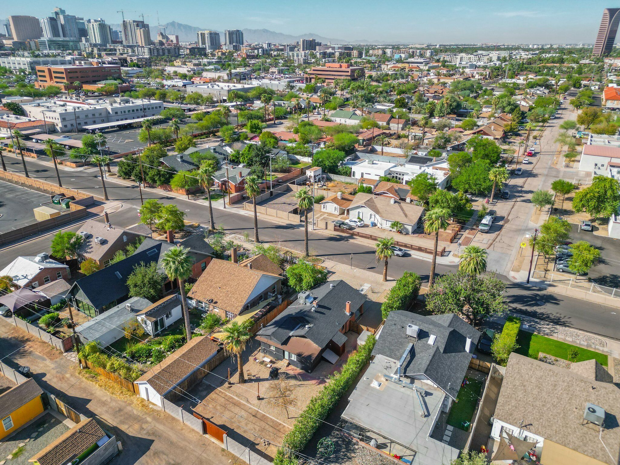 An aerial view of a residential area with houses, streets, and a distant city skyline.