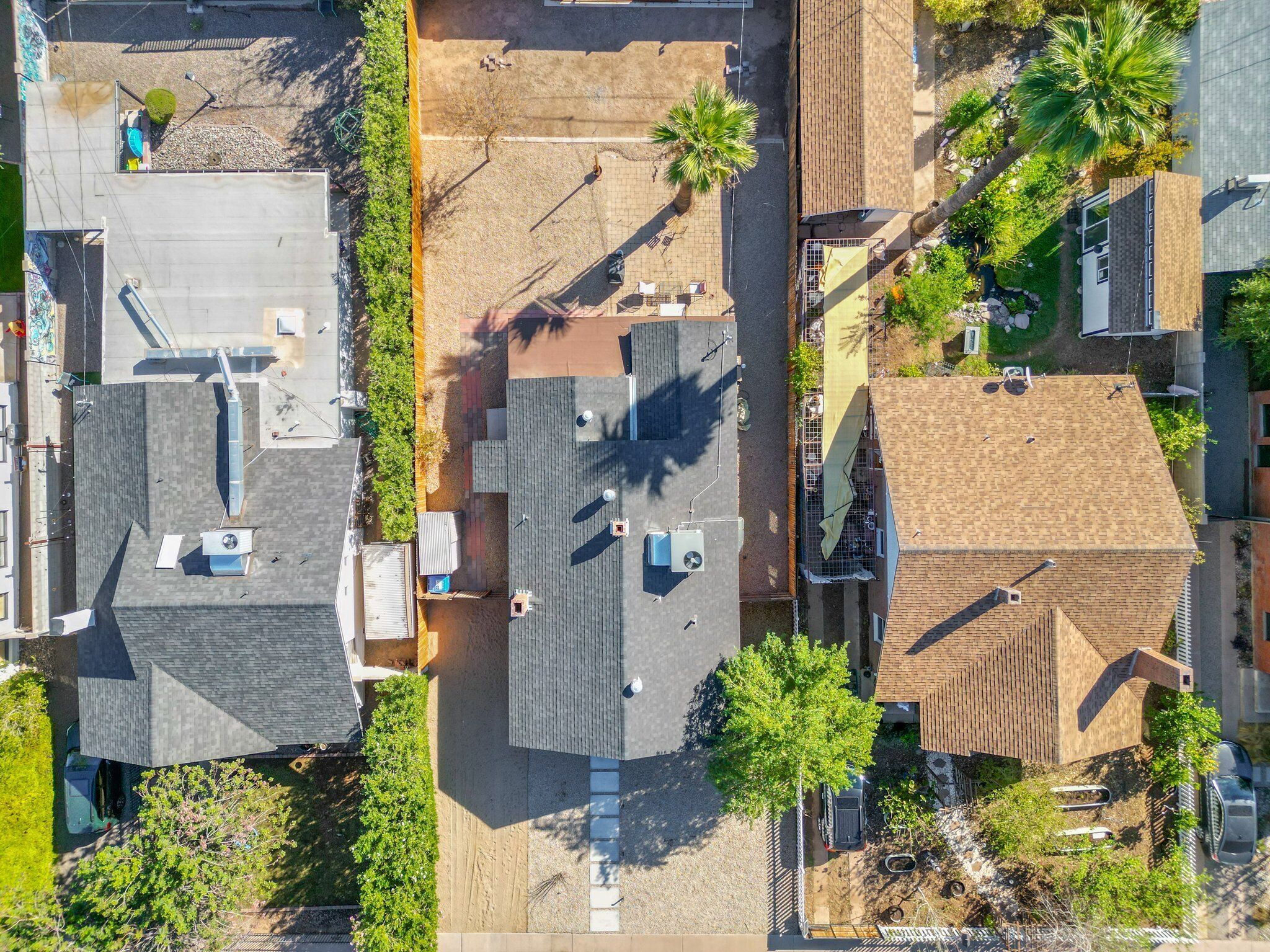 Vista aérea de uma área residencial com várias casas, um estacionamento e uma pequena área de parque com árvores e um parquinho.