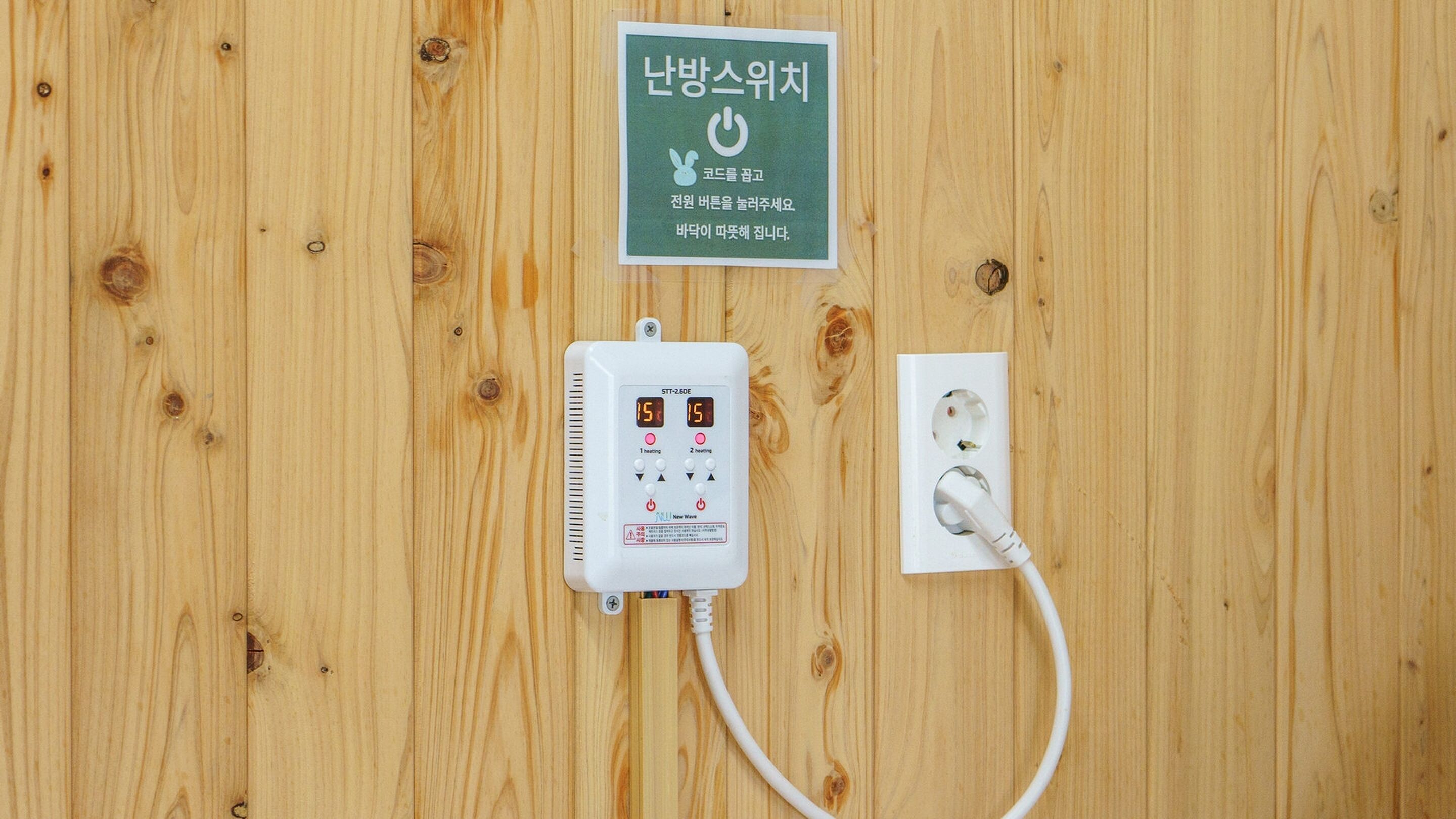 A wooden wall with a power outlet and a control unit.